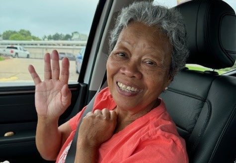 Att Callahan sits in the passenger side of a car, waving