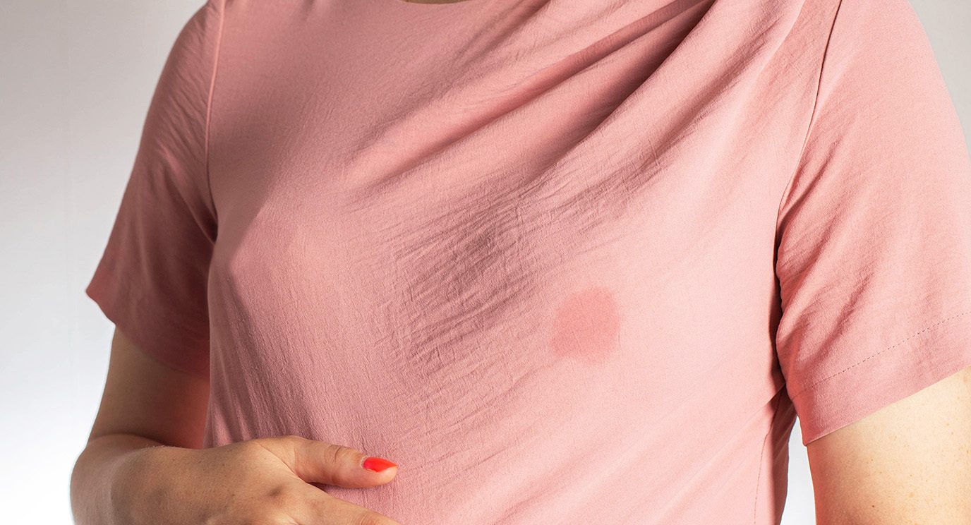 Close-up of breast leaking fluid through salmon-colored T-shirt