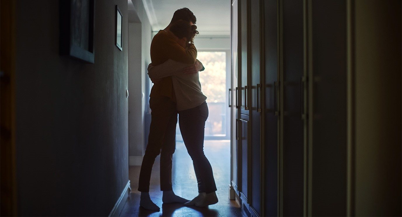 Silhouettes of a man and woman embracing in a dark hallway