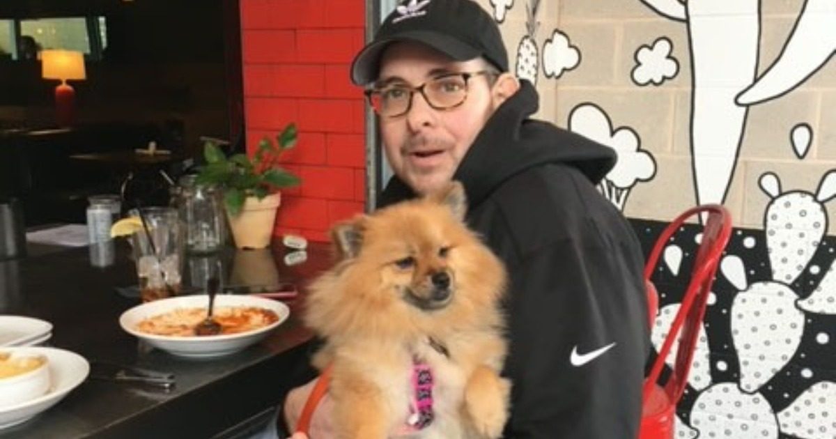 Dan Hund, with his dog, Pinto sitting down at a restaurant table.