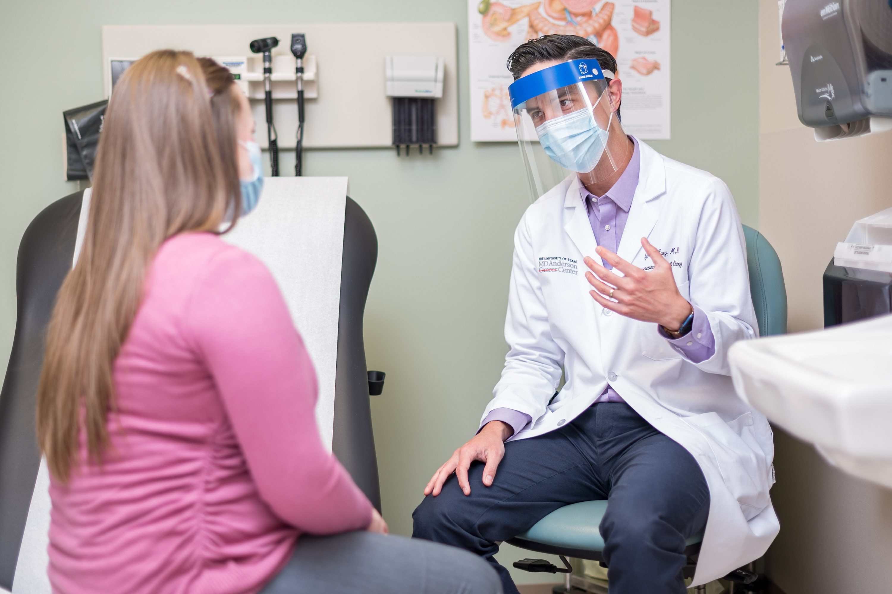 Ryan Huey, M.D., speaks with a patient while wearing a face shield over a medical-grade face mask.