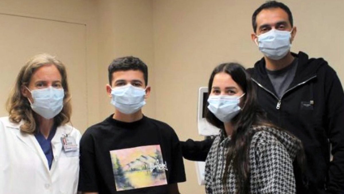 Mazen Nadim stands with his parents, along with Mary Austin, M.D., on the left. All are wearing medical-grade face masks.