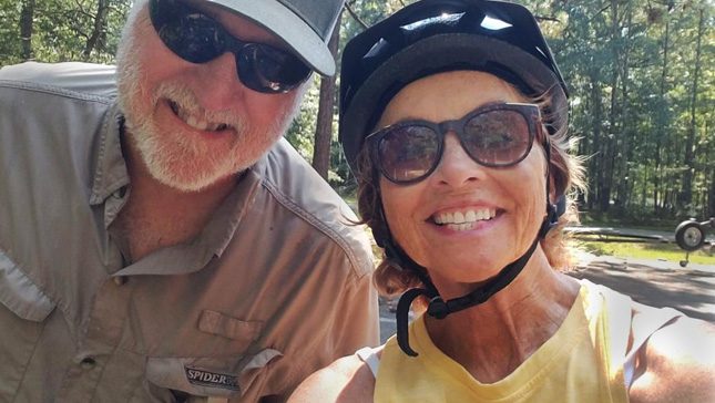 Kathy McKay and her husband smiling while riding bicycles. 