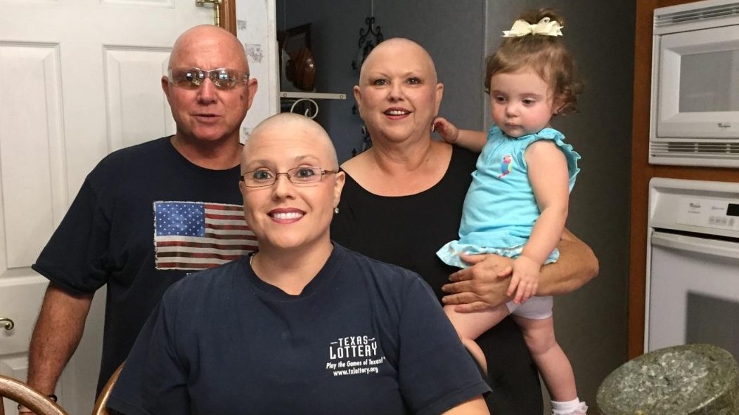 Breast cancer survivor Racheal Martin shows off her bald head with her family