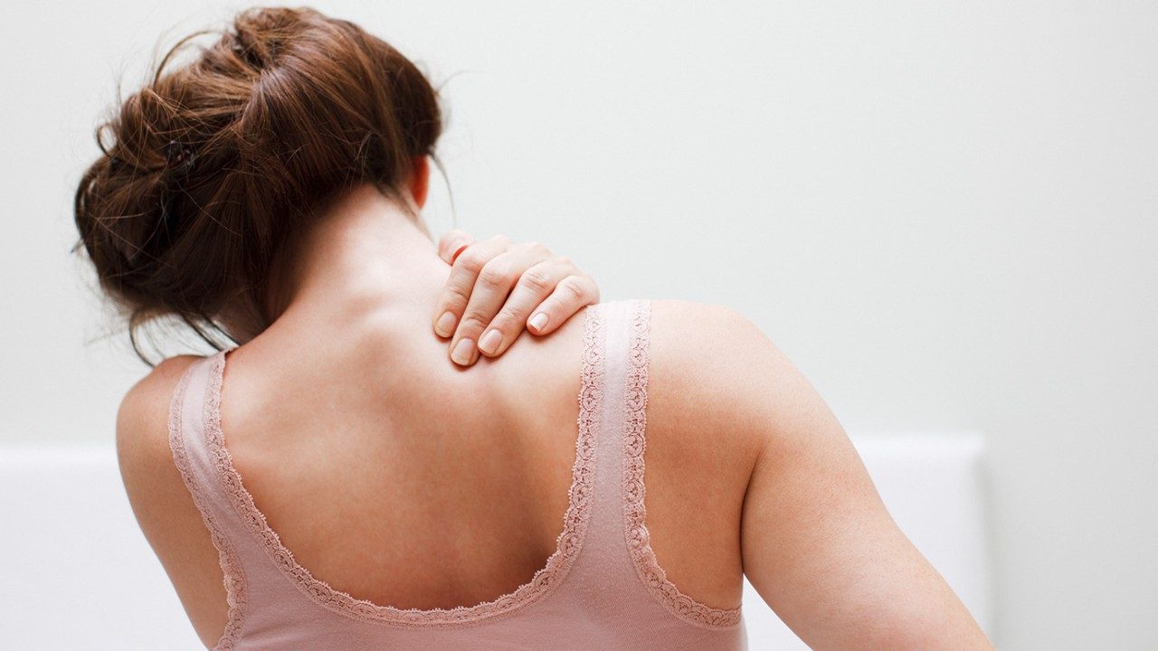 woman rubbing her back neck in pain