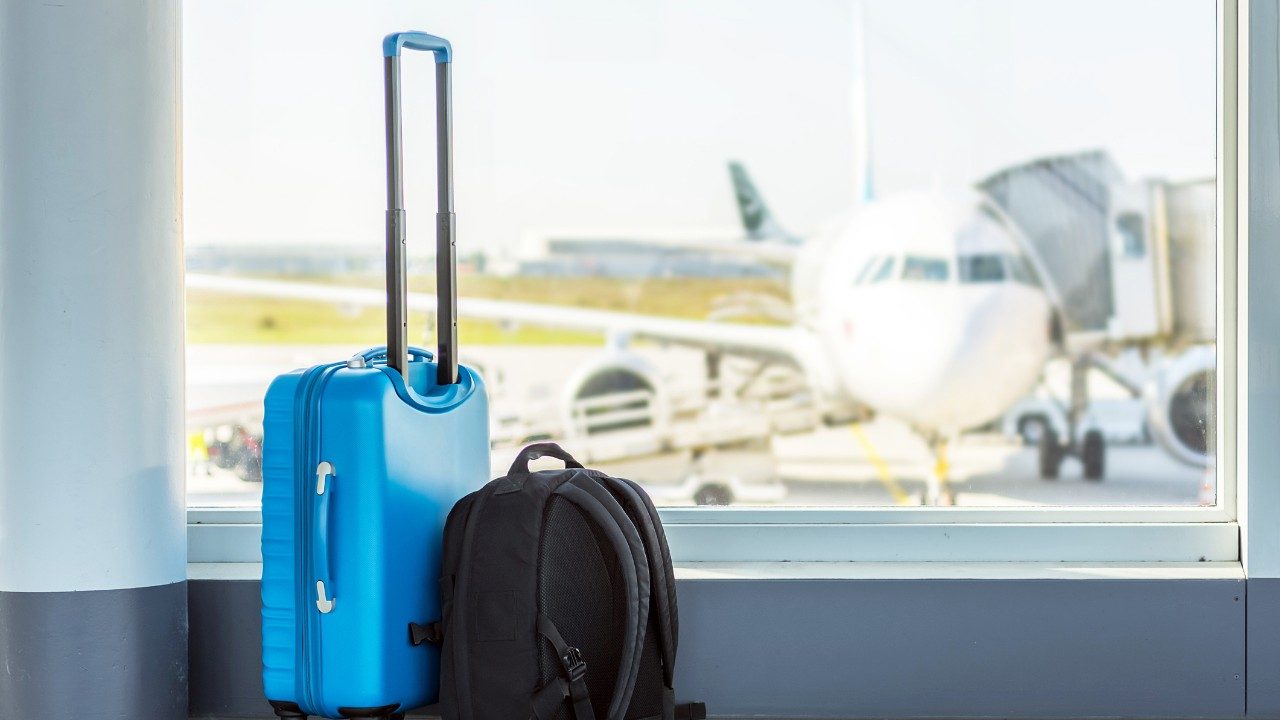 Luggage by a window overlooking the tarmac at an airport