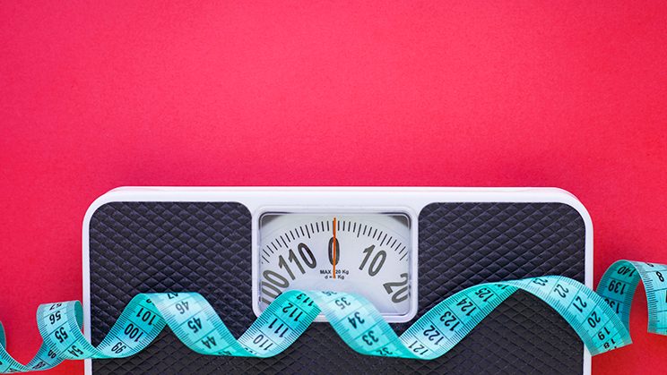 Scale and tape measure against bright pink background