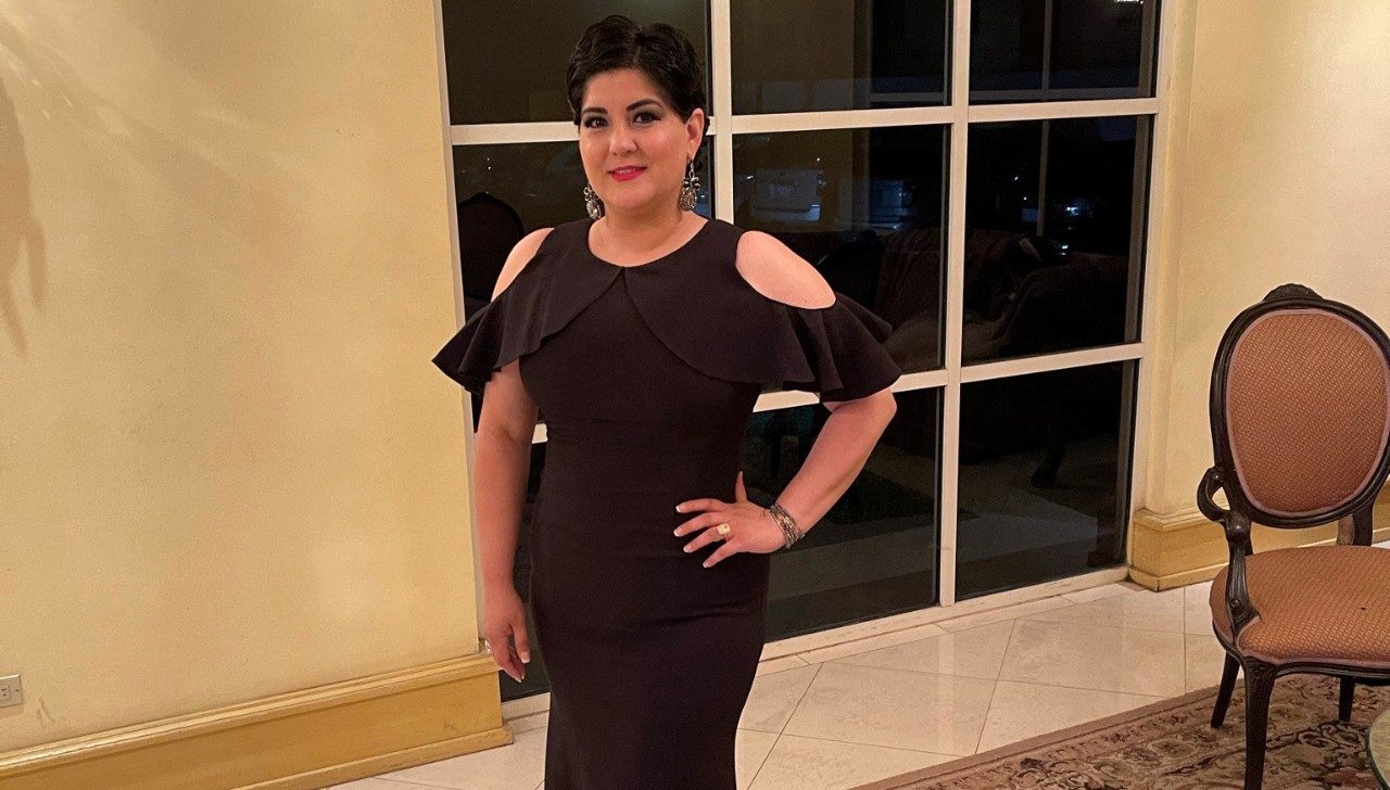 Ovarian cancer survivor Careli Ann Garza poses in a dress with a hand on her hip