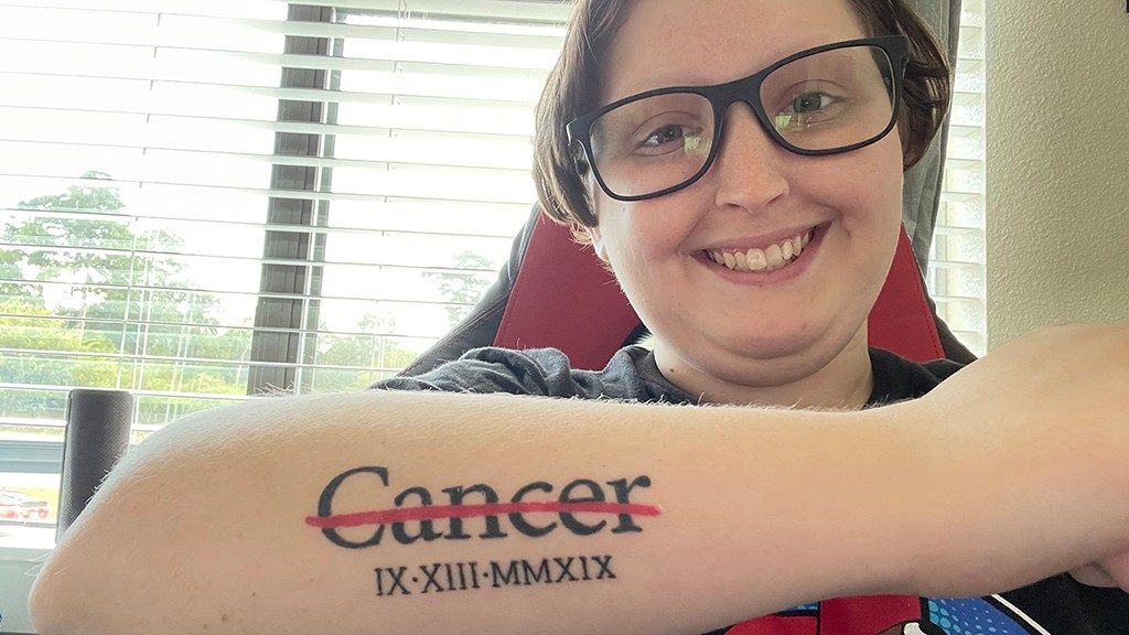 Nasopharyngeal cancer survivor Bella Lawlar shows the cancer strikethrough tattoo on her arm.