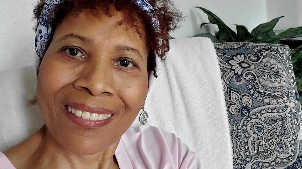 Close-up photo of pancreatic cancer survivor Reneata Benjamin smiling while wearing a headband.