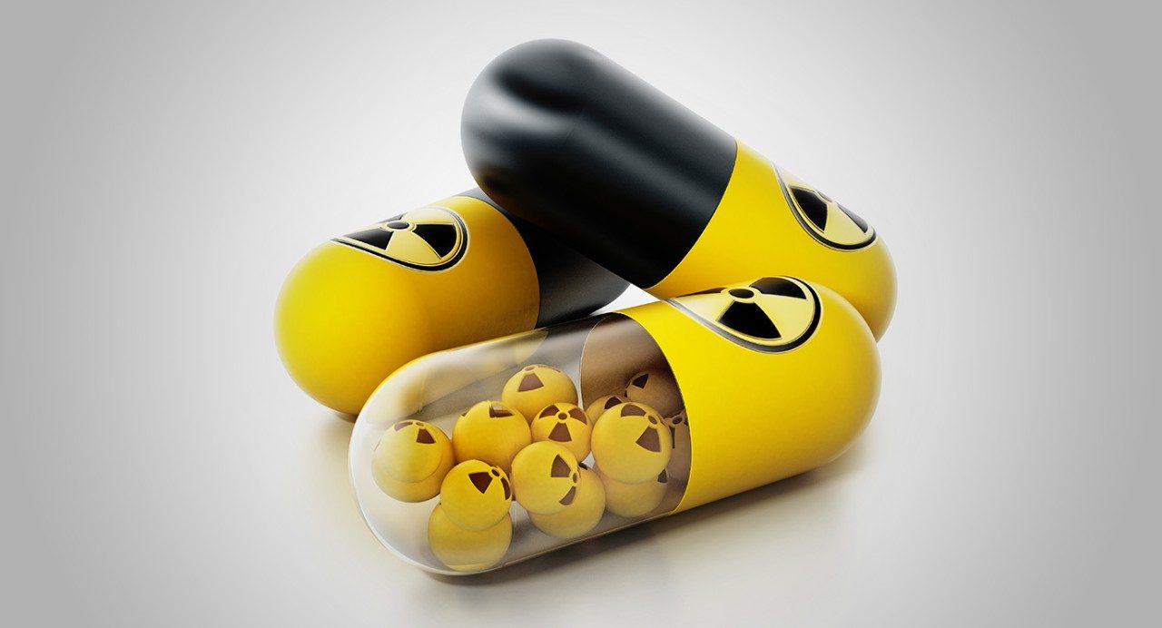 Stylized depiction of yellow/black medicine capsules emblazoned with radioactive warning symbol