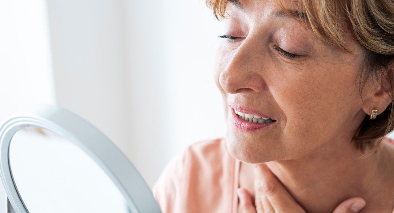 Close-up of Senior woman analyzing her face in the mirror .