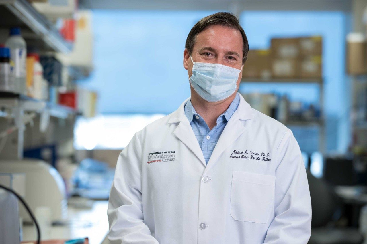 Dr. Michael Curran faces the camera with his lab in the background.