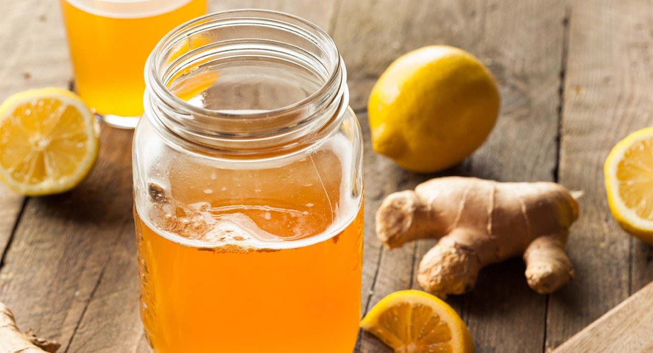 Jar of kombucha is shown with lemon and ginger