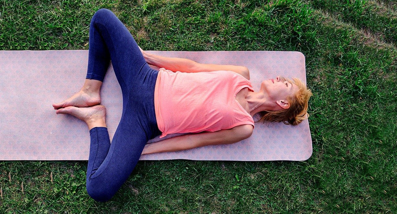 Image of a woman lying on a yoga mat stretching her legs