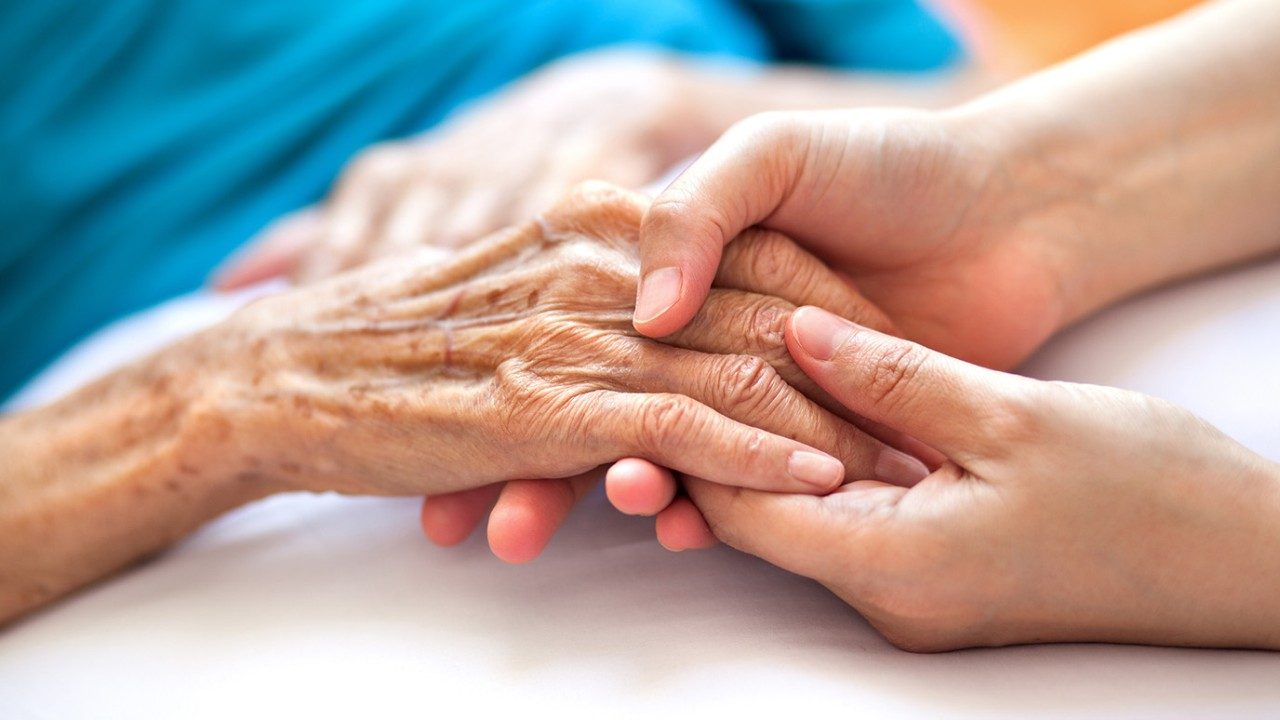 Woman holds the hand of an elderly woman