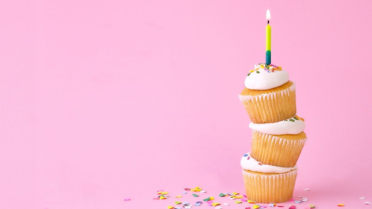 Three cupcakes stacked in a tower with one candle on top