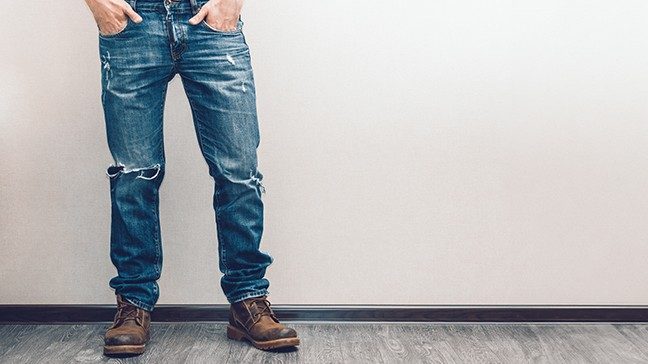 Waist down view of fit young white man in blue jeans and work boots with hands in pockets