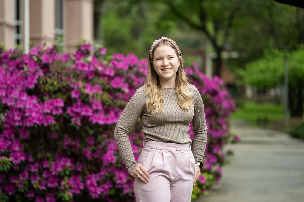 Savannah Kaspar stands in front of an azalea bush on campus