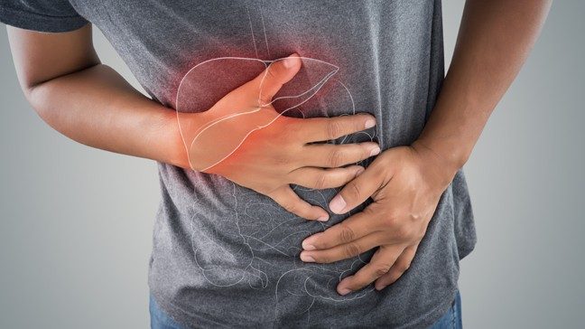 Waist-level shot of young fit man in gray T-shirt holding abdomen in pain