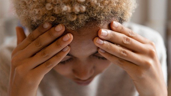 Woman rubs her forehead with both hands