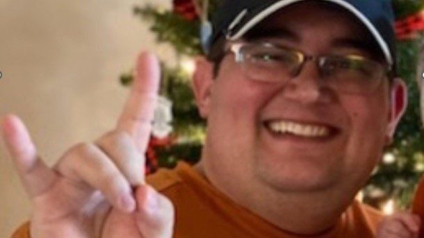 Michael Morin smiles holding up the Texas Longhorns sign with his hands