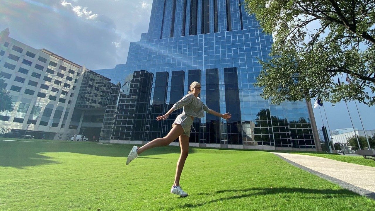 Macey Hicks jumping excitedly in front of an MD Anderson building