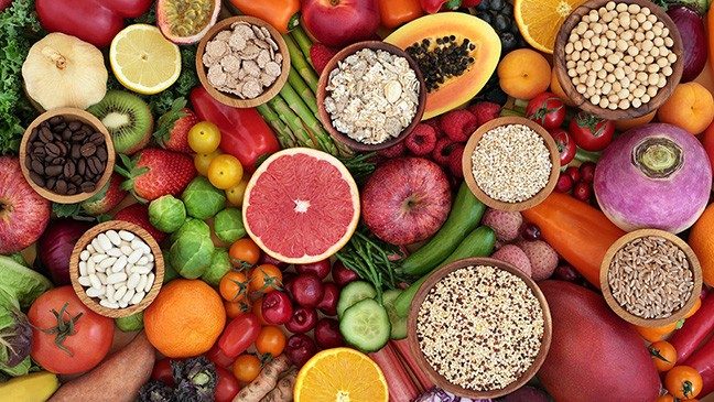 Aerial image of foods including papaya, chickpeas, quinoa, oats, grapefruit, cucumber, tomatoes, oranges, lemons, apples, coffee beans, ginger, brussels sprouts, strawberries, kale, rhubarb, asparagus and raspberries