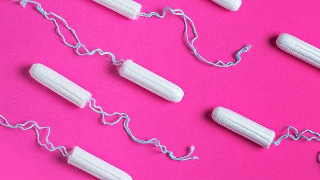 White tampons with blue strings against a hot pink background