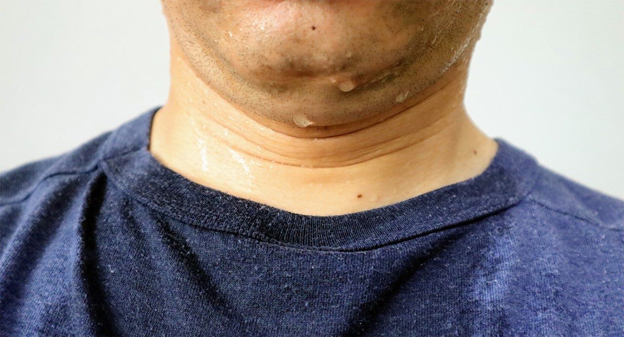 Close-up of man's sweaty neck, chin, and wet dark blue T-shirt collar