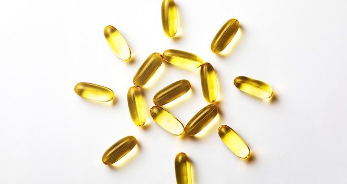 Yellow supplement capsules arranged in the shape of a sun