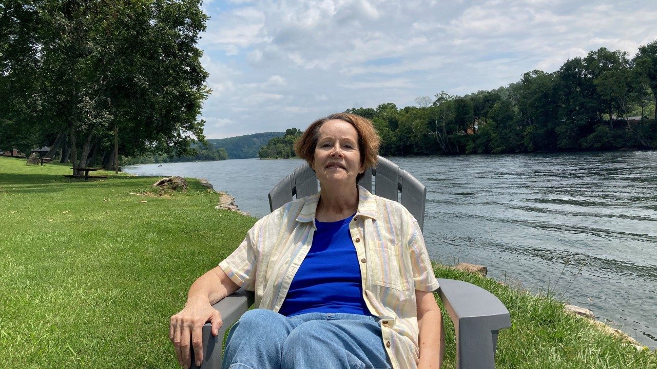 Diane White sits in a chair by the water