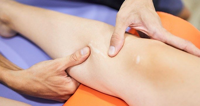 Close-up of hands massaging a woman's calf