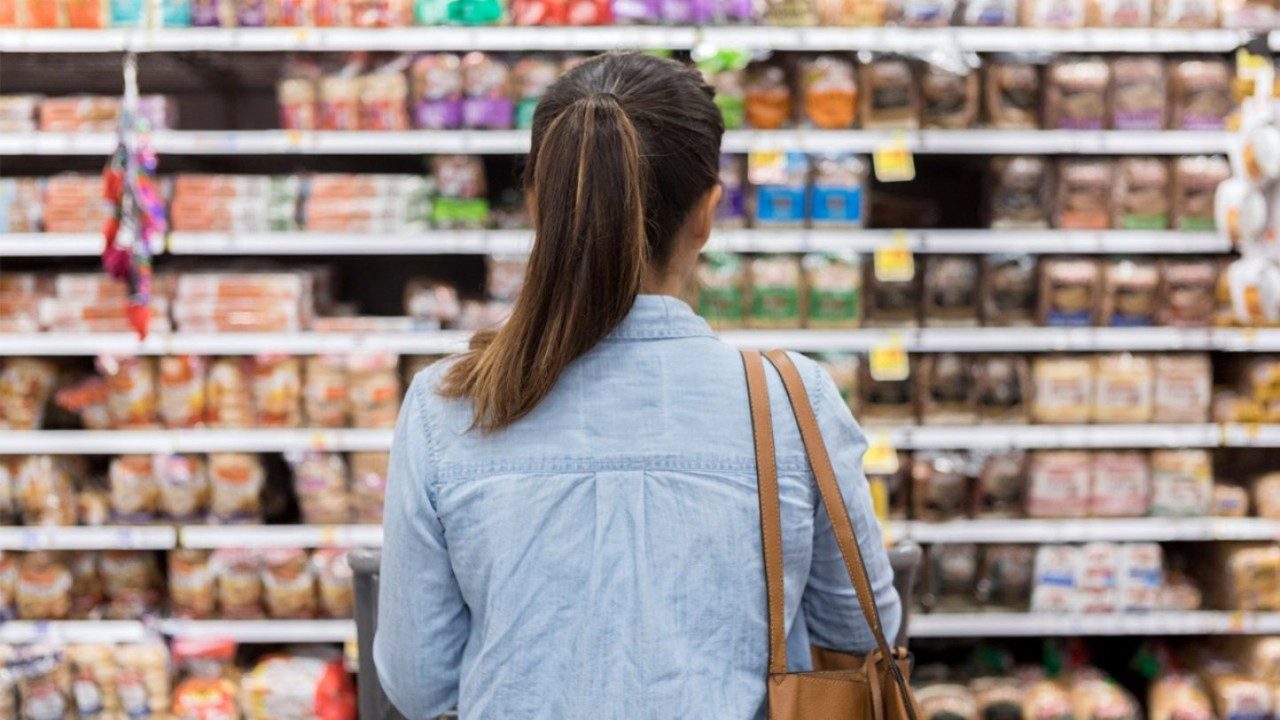 Unidentified dark-haired woman stares at dizzying array of choices on grocery shelf