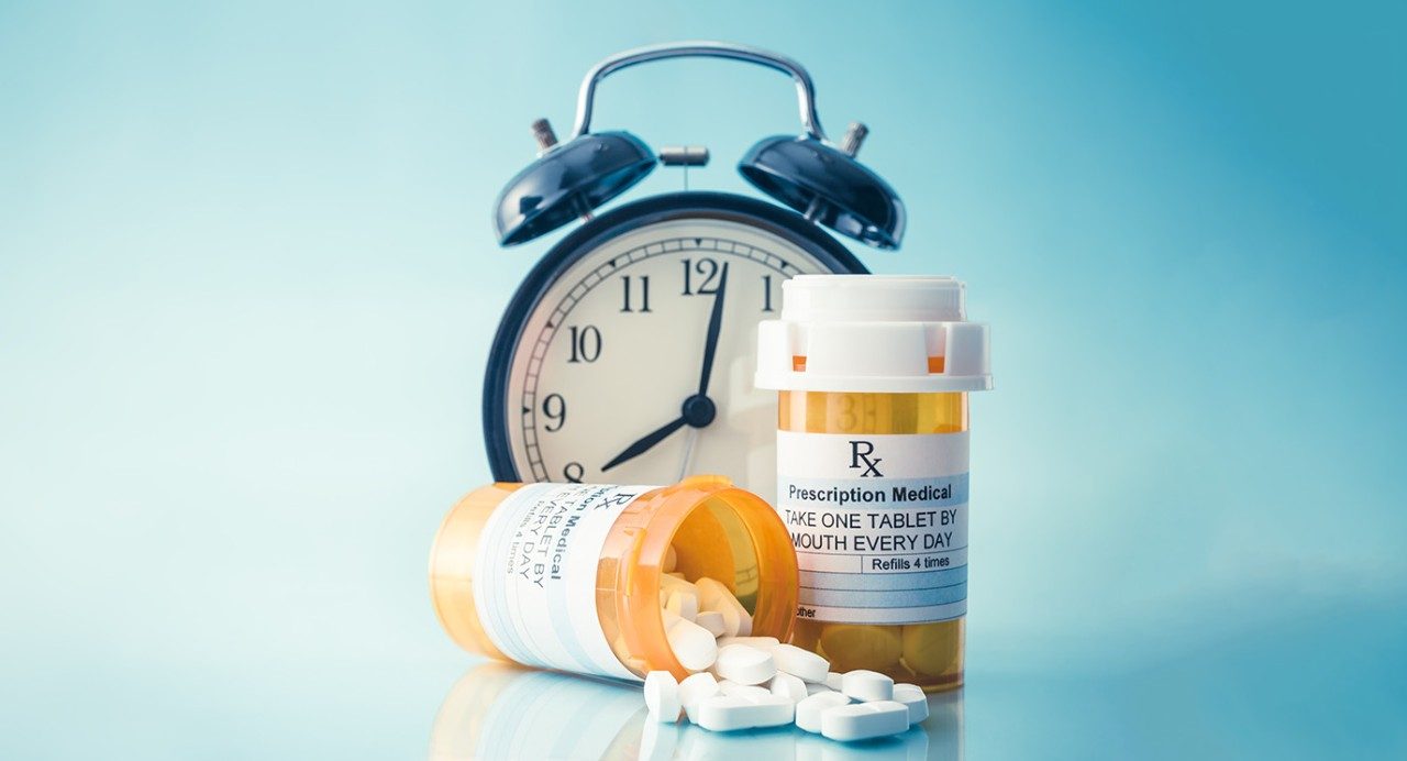 Close-up of old-school alarm clock with two prescription medication bottles