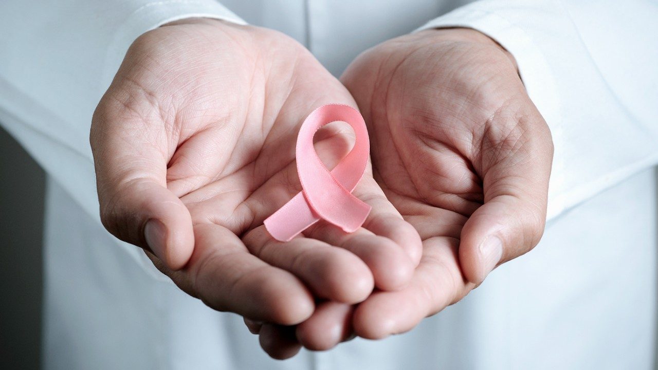 Man holds pink breast cancer ribbon in his hands