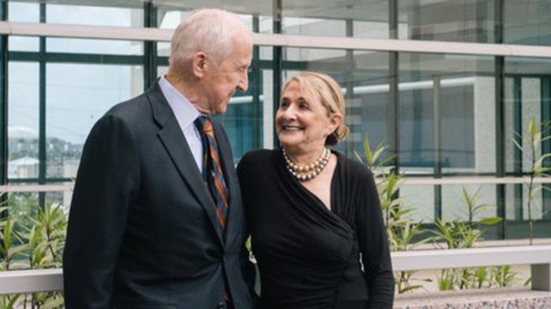 Man in suit smiles at woman wearing black blouse